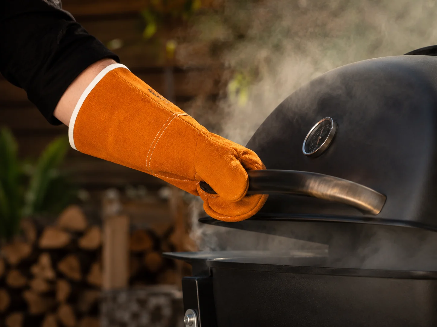 Manopla larga sujetando el asa de la tapa caliente de una barbacoa